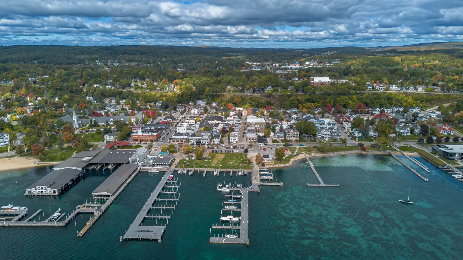 Aerial view of Harbor Springs, Michigan, in autumn: the harbor, marina and downtown on Little Traverse Bay, with wooded hills behind.