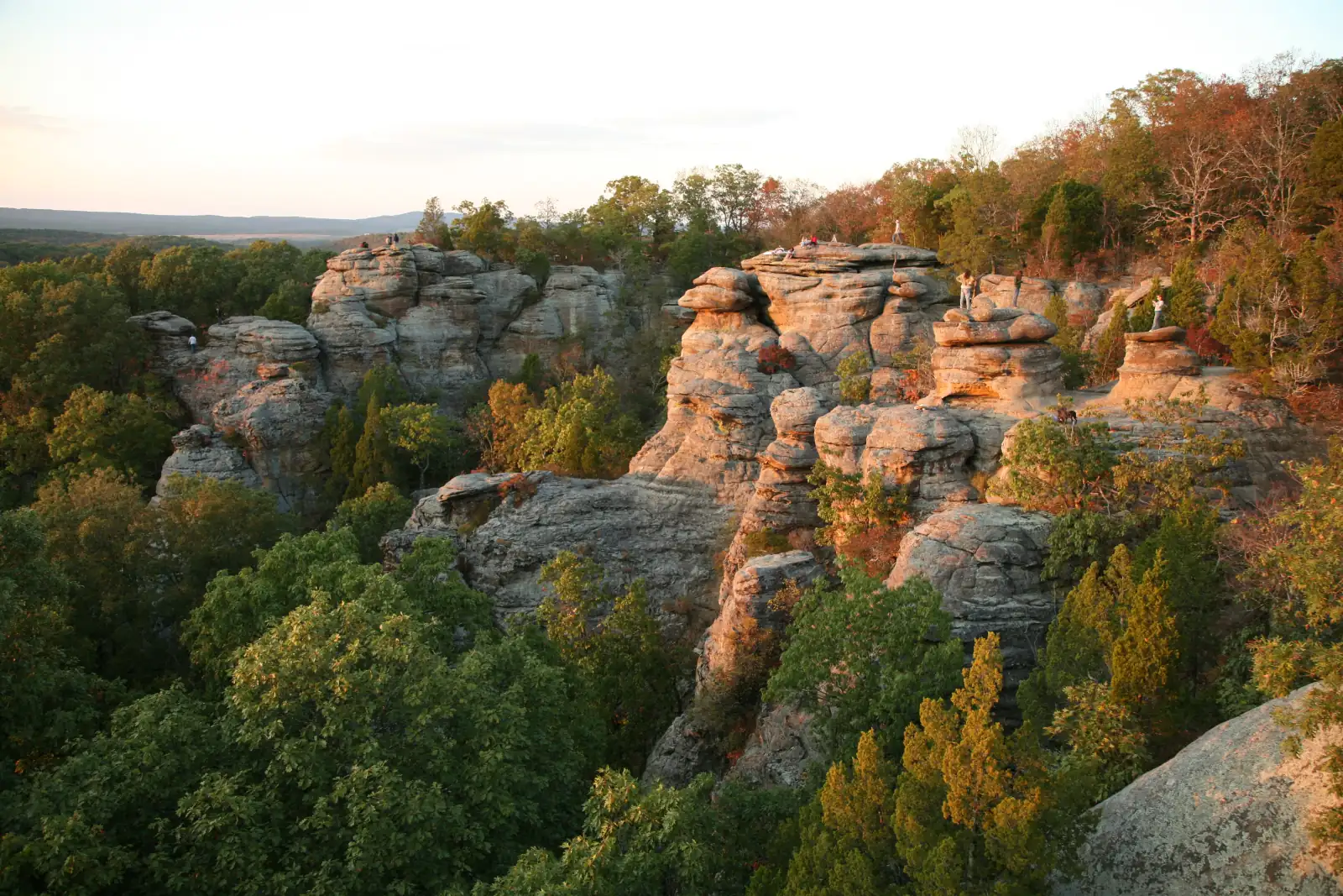 Sandstone rock formations glow in evening light above autumn-colored woods at Garden of the Gods in the Shawnee Hills of southern Illinois.