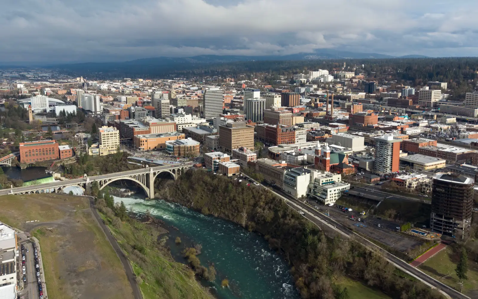 Aerial view of downtown Spokane with the Spokane River and the arched Monroe Street Bridge in the foreground.